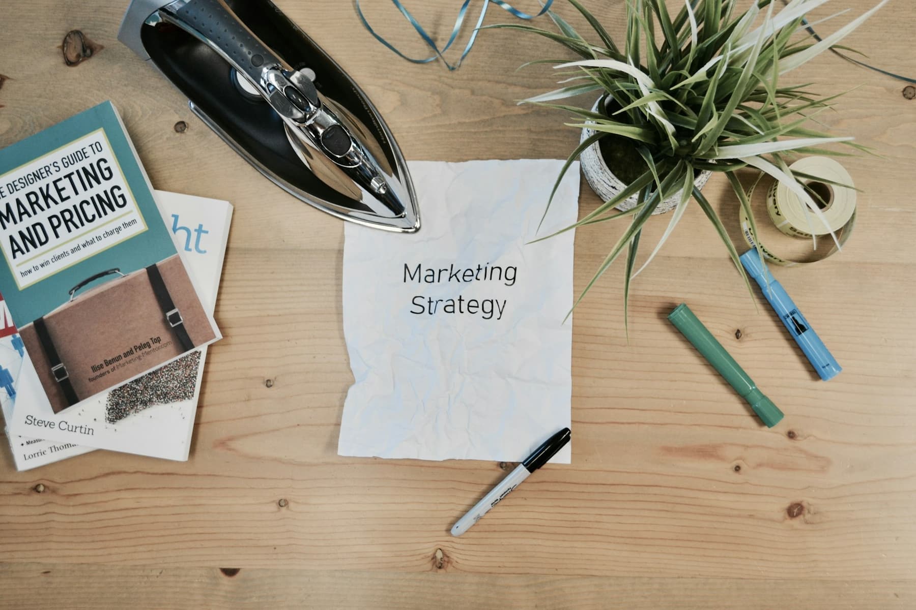A desk with a marketing strategy note, a pen and a book on marketing and pricing.